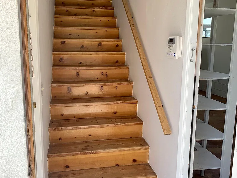 Hall with stairwell that goes to upstairs living space and door to the right goes into open studio space downstairs