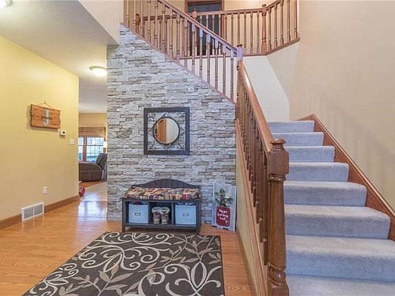 The 12X10 2-story foyer boasts visually appealing accents such as a stacked stone wall, a turned staircase & hardwood floors.