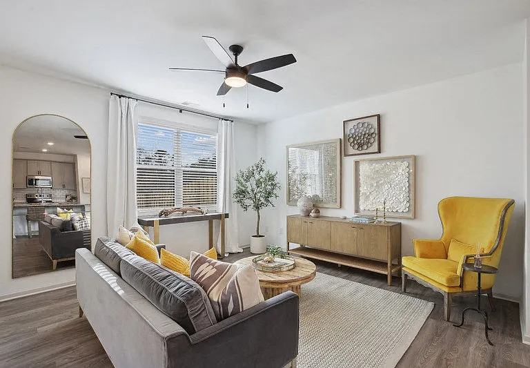 Bright living room featuring a large couch and abundant natural light through expansive windows.