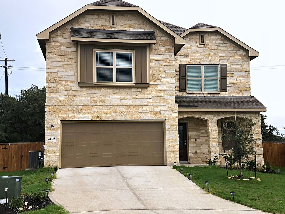 Charming two-story stone-and-brick home with a two-car garage and tidy front lawn.