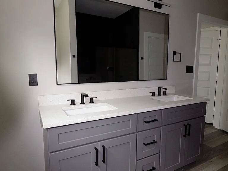 Modern primary bathroom featuring double vanity with quartz countertops, sleek fixtures, and excellent lighting. Clean, contemporary design.
