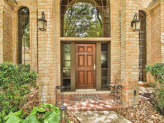 The covered porch is accented by stately columns, tall windows, and lush landscaping