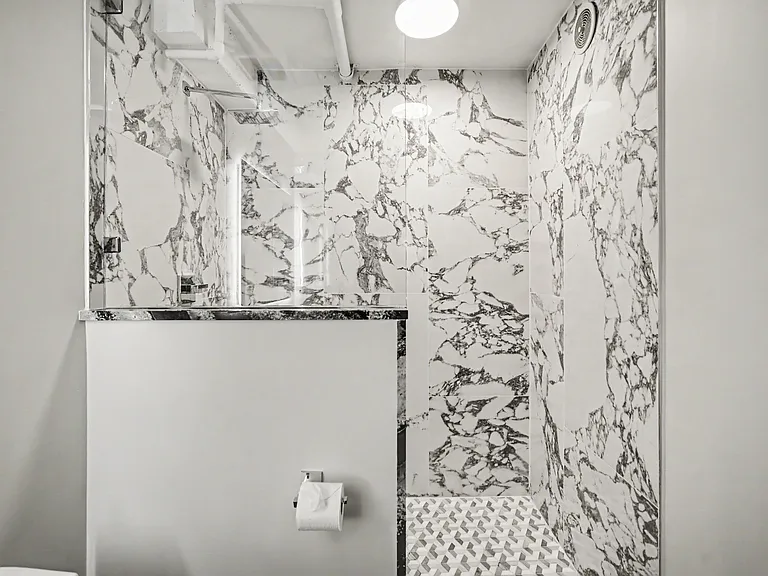 Guest bathroom next to the office features backlit mirror, wide sink, beautiful marble-like shower with rain shower head and a modern bidet