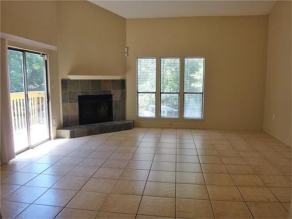 Living room with tile flooring, high ceiling, wood burning f