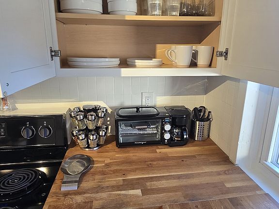 Fully stocked kitchen with dishes, glassware, cookware, utensils, and small appliances.
