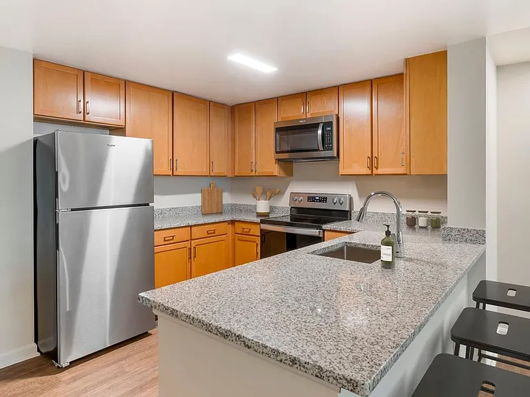Updated Finishes kitchen with grey speckled granite countertops, oak cabinetry, stainless steel appliances, and hard surface flooring