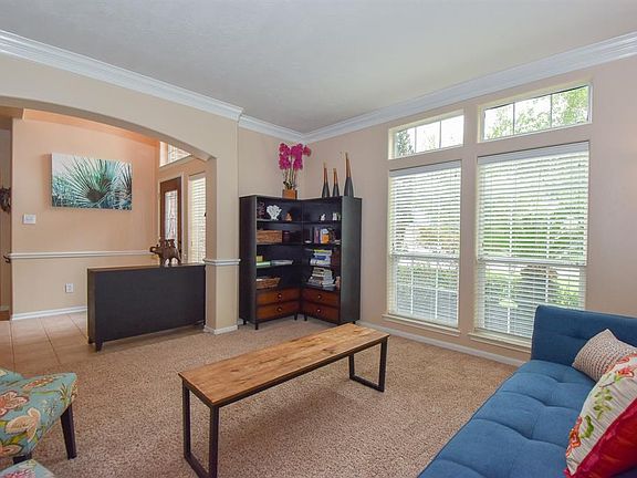 An arched entry to the formal living room boasts transom windows, crown molding, blinds, neutral paint and carpet