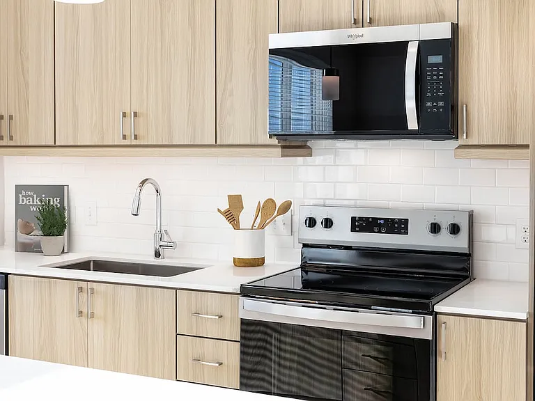 Finish Package II kitchen with stainless steel appliances, oak cabinetry, white tile backsplash, and white quartz countertop