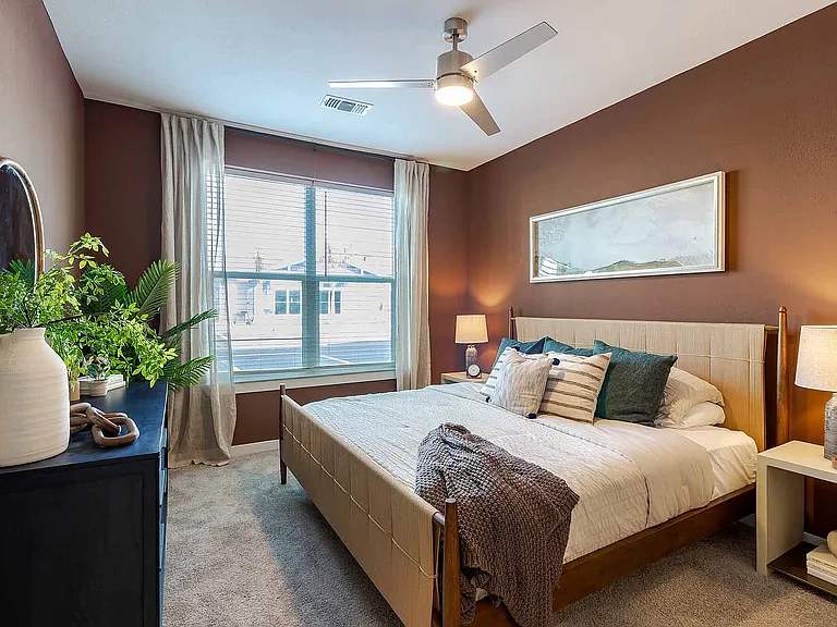 Retreat to a restful bedroom featuring a rich accent wall, plush carpeting, and a large window that fills the room with natural light.
