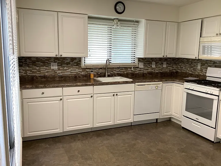 Updated kitchen with new appliances and white cabinets with updated countertops and glass tile backsplash