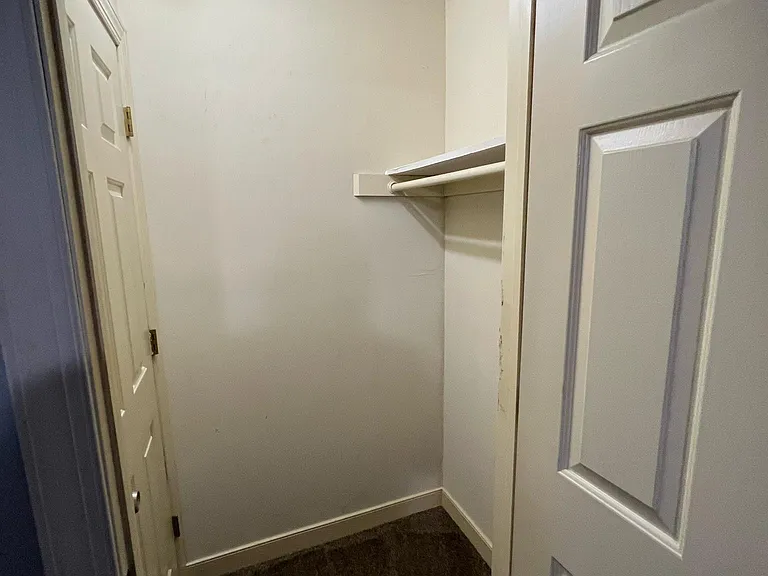 Bedroom 1 photo looking into 3rd closet of the room. Door to attic stairwell pictured on the left