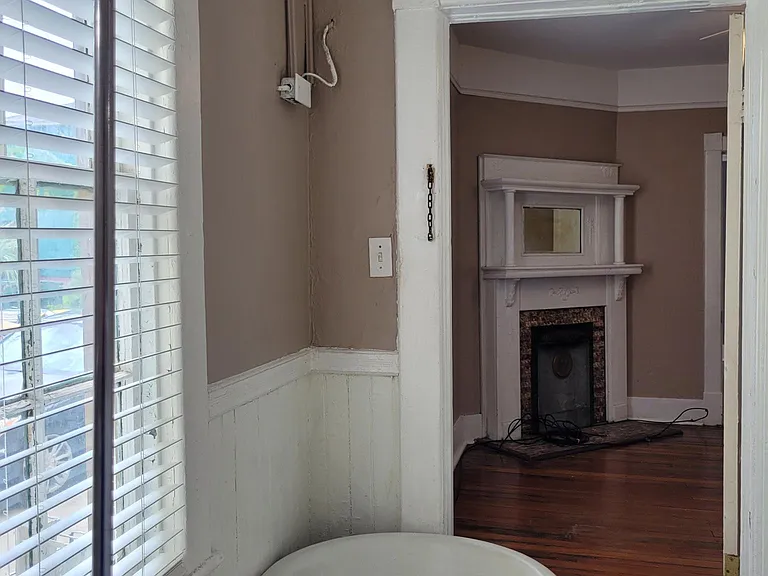 Bathroom - Original clawfoot bathtub & slate tile floor. View of fireplace in dining room, and back bedroom beyond through the door