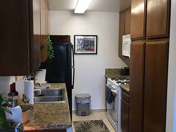 Kitchen has ceramic tile flooring and granite counters. Microwave oven is over the stove.