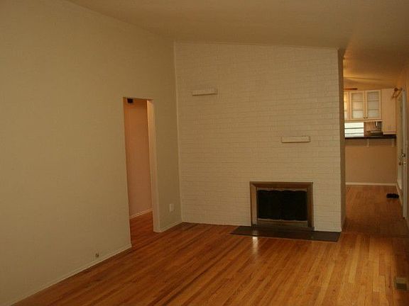 Closer view of painted brick fireplace w/built in brick shelves; cathedral ceilings open up the room