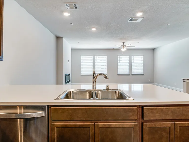 Kitchen island featuring a stainless steel double-basin sink, contemporary faucet, and light-toned countertop