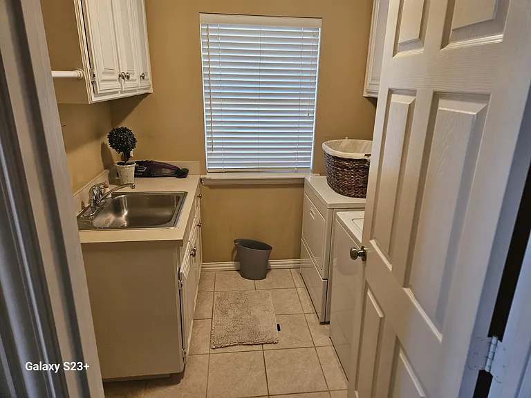 Full laundry room with stainless steel sink and included washer and dryer