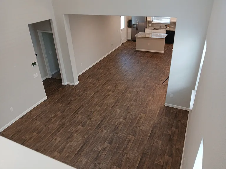 Living room displays the open floor plan that connects to the dinning room and modern kitchen in the background. Entryway to the left leads to the primary bedroom