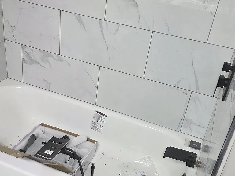 Secondary bathroom marble tiled tub/shower combo with black fixtures