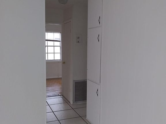 Hallway with storage leading to 2 rooms and bedroom