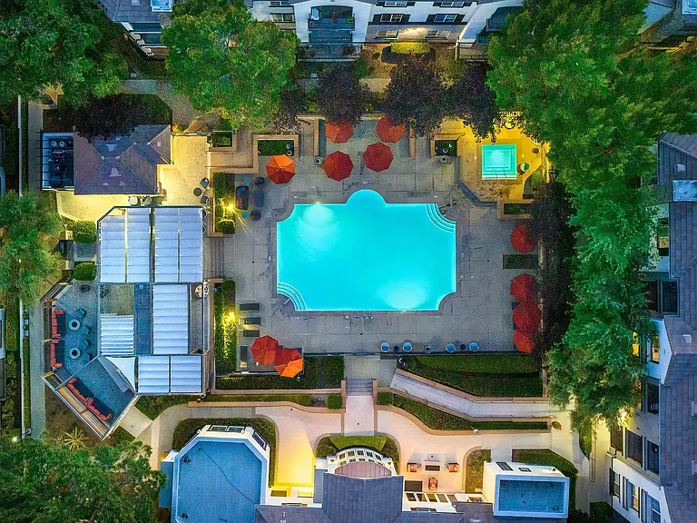 Vibrant Nighttime View of Pool Surrounded by Trees and Seating