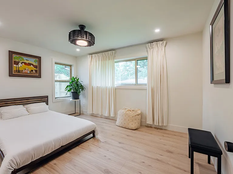 Bright, naturally lit secondary bedroom with ceiling light and fan and custom built-in cabinets_ideal for family, guests, or a home office.