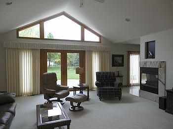 A grand living room with cathedral ceiling & 2 sided gas fireplace