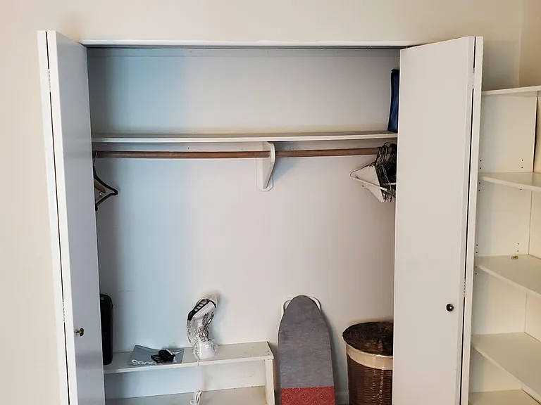 Bedroom closet with double doors, hanging rod, and built-in shelving for organized clothing and household storage.