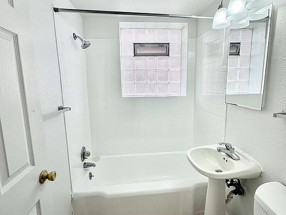 Bright and modern bathroom featuring a sleek white sink, bathtub, and elegant tiled flooring.