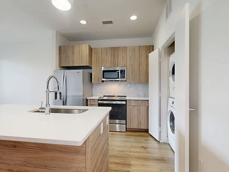 Apartment Kitchen with Stainless Steel Appliances, white counter tops and wood-style flooring.