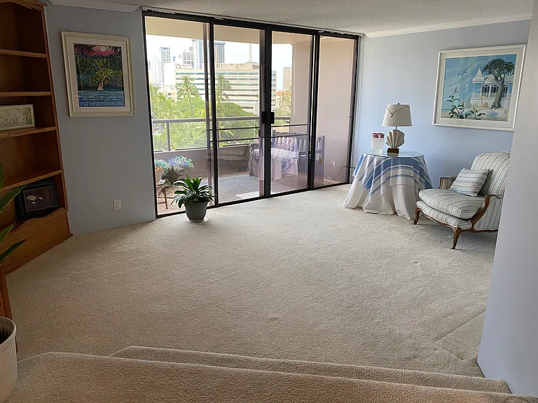 Living room with built in entertainment center and cabinet; all lanai doors and windows tinted against sun.