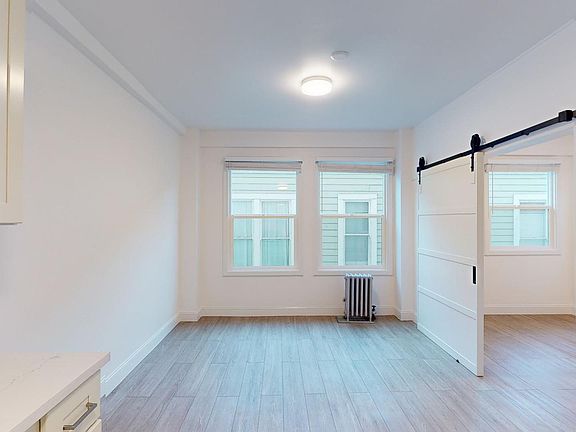 Sunlit room with a large window and wood-like flooring