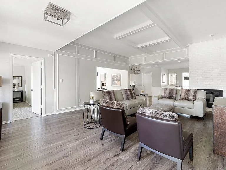 Living room with LVP floors, a fireplace, a decorative wall, and coffered ceiling