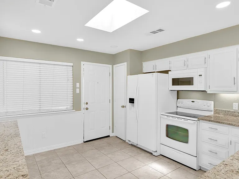 Freshly painted cabinets, new hardware, new door into the garage. The skylight streams light into the large kitchen space.