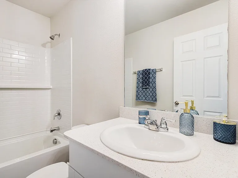 Bathroom featuring a white bathtub with subway tile surround, chrome showerhead and faucet, and a vanity with an integrated sink