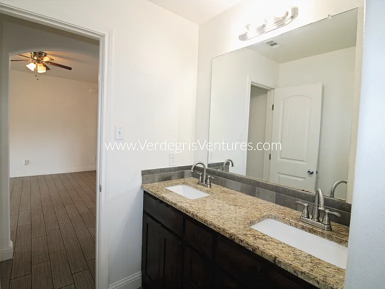 Hall bathroom has dual sinks and storage