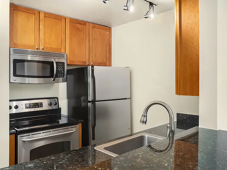 kitchen appliances, cabinets, sink, counters. Higher cabinet in the foreground is a "breakfast bar".