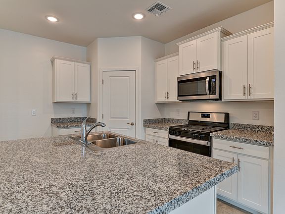 The Olive floorplans kitchen featuring white cabinets and speckled countertops.