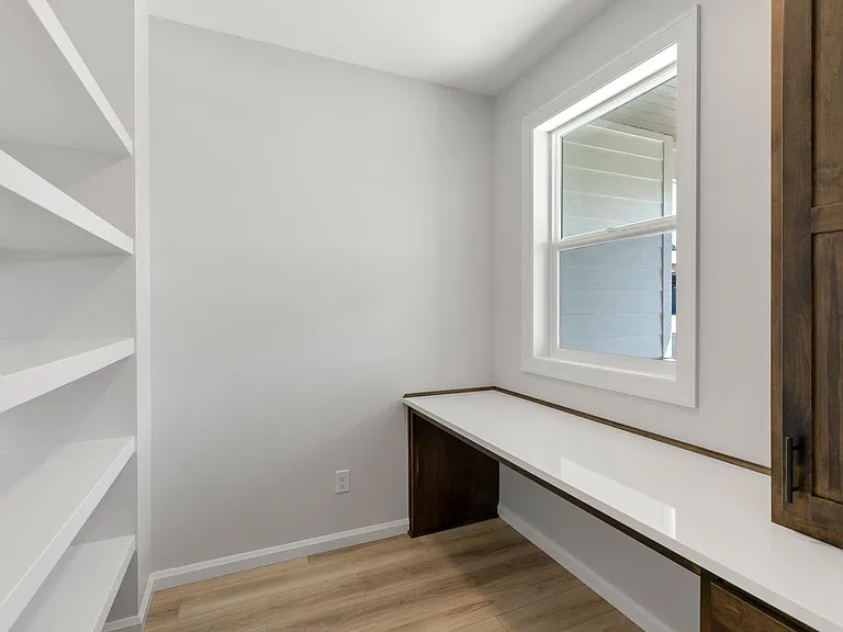 Home office with built in desk with cabinets and shelves.