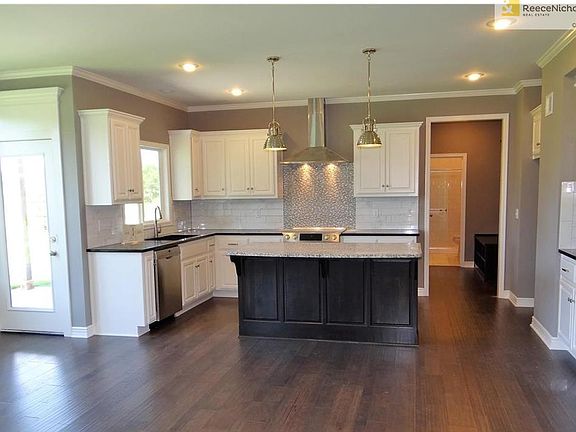 Kitchen is complete with granite counter tops, center island, tiled back splash, smooth top slide in range with vented hood, snack bar with microwave & enameled cabinets.