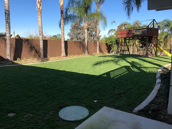 Backyard with lawn and large child s play structure, fenced