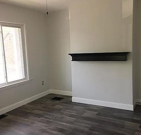 Living room featuring exposed brick, ceiling fan and mantle.