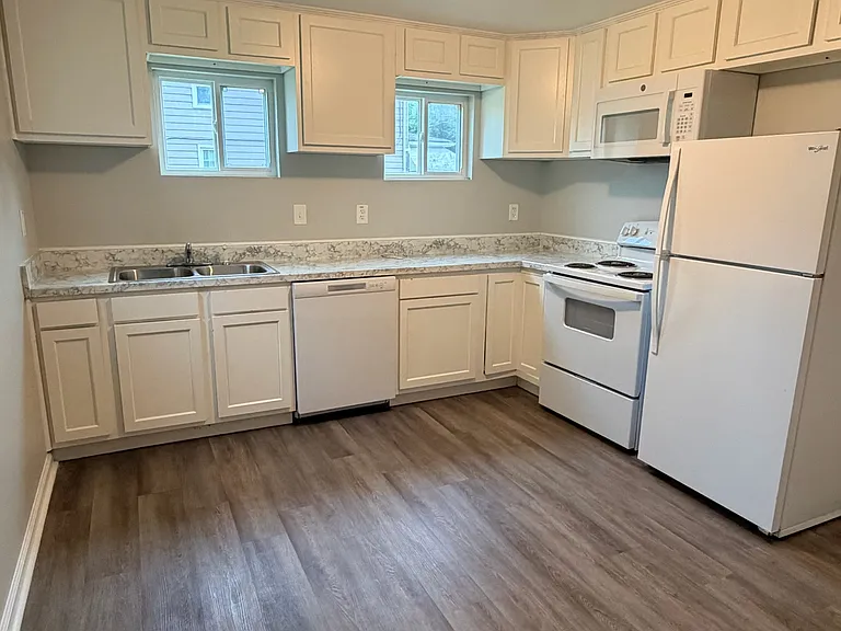 Full-size eat-in kitchen featuring a refrigerator, oven, microwave, sink, generous countertop space, and ample cabinet storage.