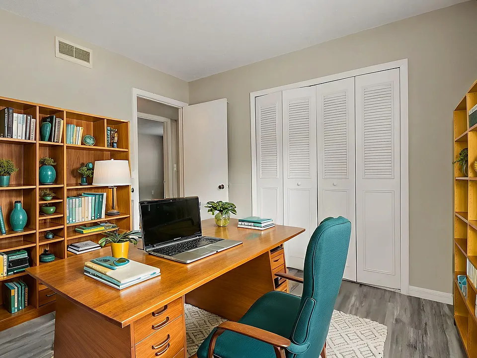 Inviting home office with stylish wooden desk, cozy teal chair, and well-organized bookshelves, perfect for productivity and focus.
