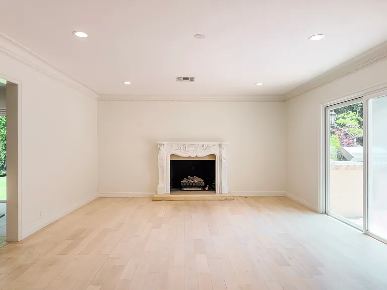 Ornate fireplace mantel and a sliding glass door to the patio define this Beverly Hills luxury rental living room at 1094 Garden Lane, a distinguished 90210 home for rent.