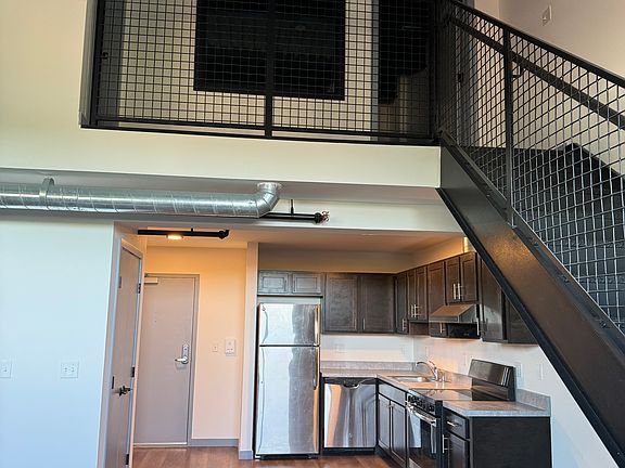 Kitchen area with Stainless Steel Appliances, open concept to living room area and stairs to the loft and bedroom