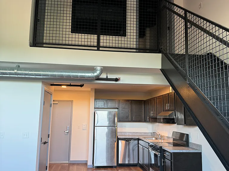 Kitchen area with Stainless Steel Appliances, open concept to living room area and stairs to the loft and bedroom