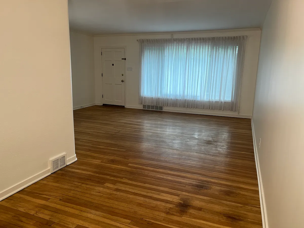 Main room with dining area (9' x 10') and living area (18' x 15'). Front door on left. - 1419 Beechwood Blvd