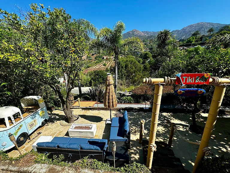 outdoor tiki lounge with two areas that provide cozy outdoor living room furniture, a gas fire pit, and a VW bus tiki bar