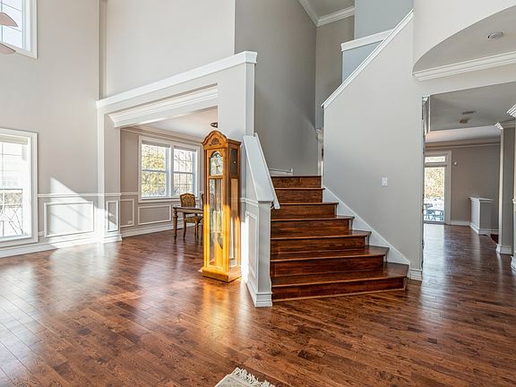 View from front door of dual staircase and light filled Living Room
