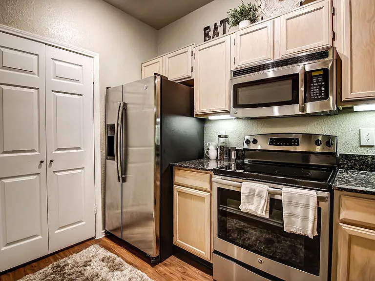 Stunning kitchen with hardwood style flooring, light colored cabinetry and stainless steel appliances
